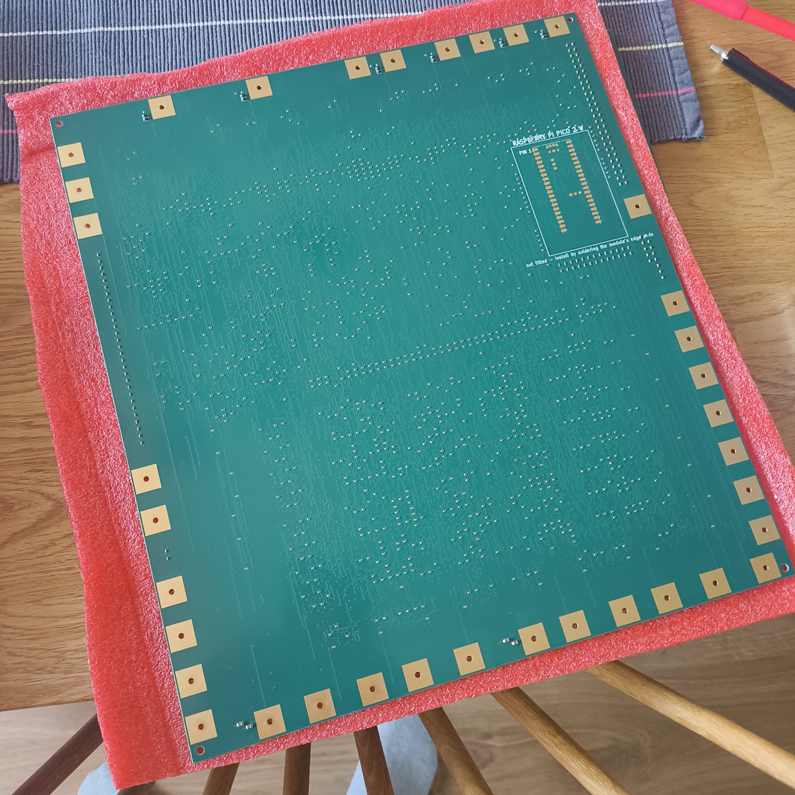 Underside of the board: mostly bare green solder mask with
         thousands of vias, the unpopulated Raspberry Pi Pico 2 W site silkscreened at top right.