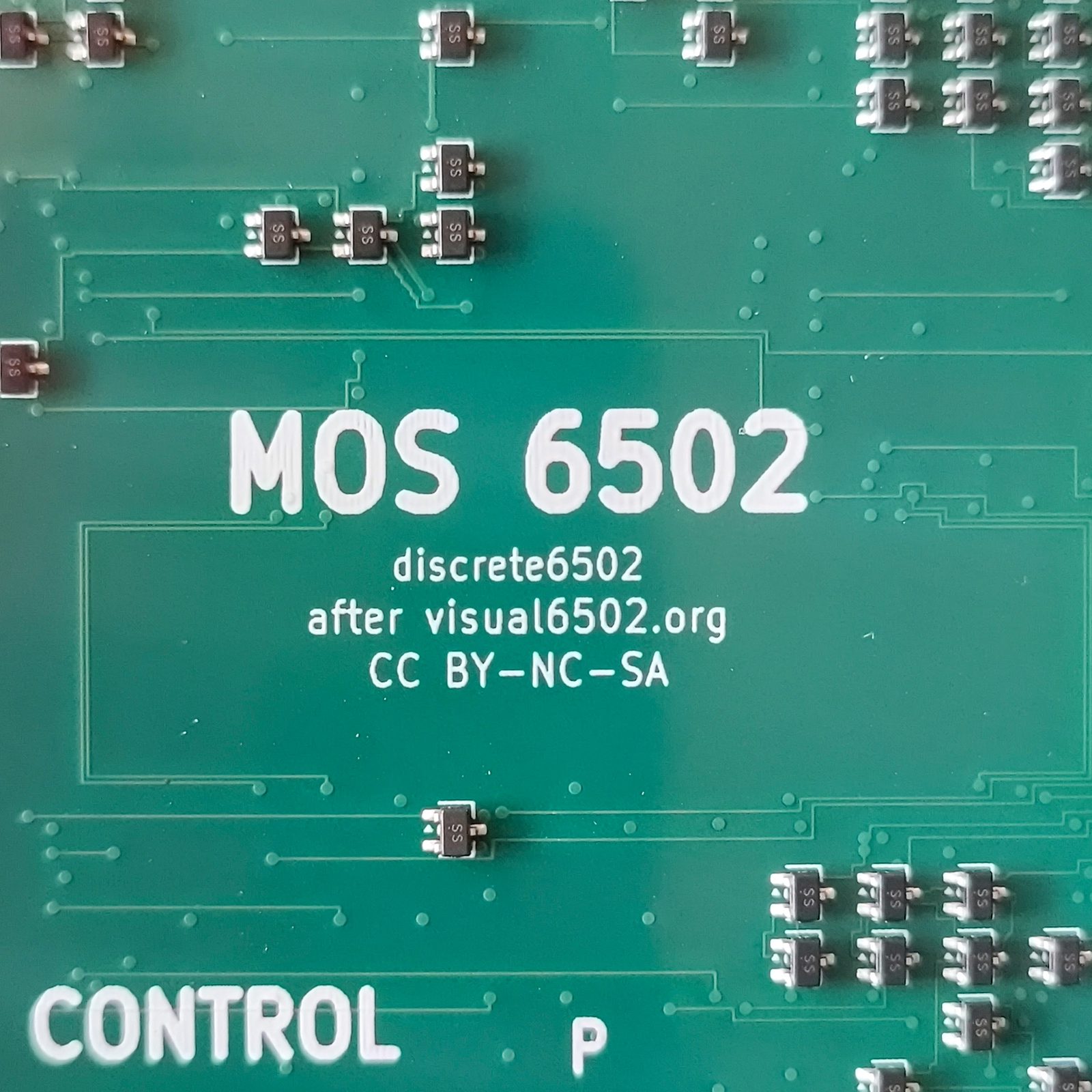 Close-up of the silkscreen reading MOS 6502, discrete6502,
         after visual6502.org, CC BY-NC-SA, surrounded by SOT-323 transistors.